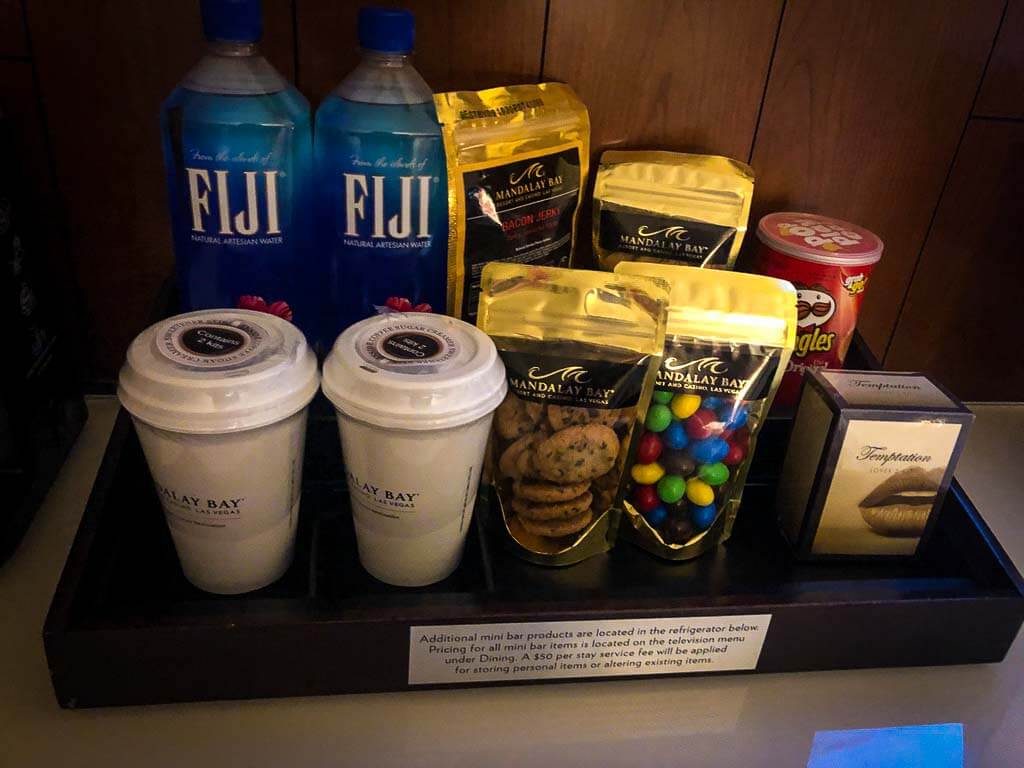 mini bar with fuji water, coffee cups and various snacks