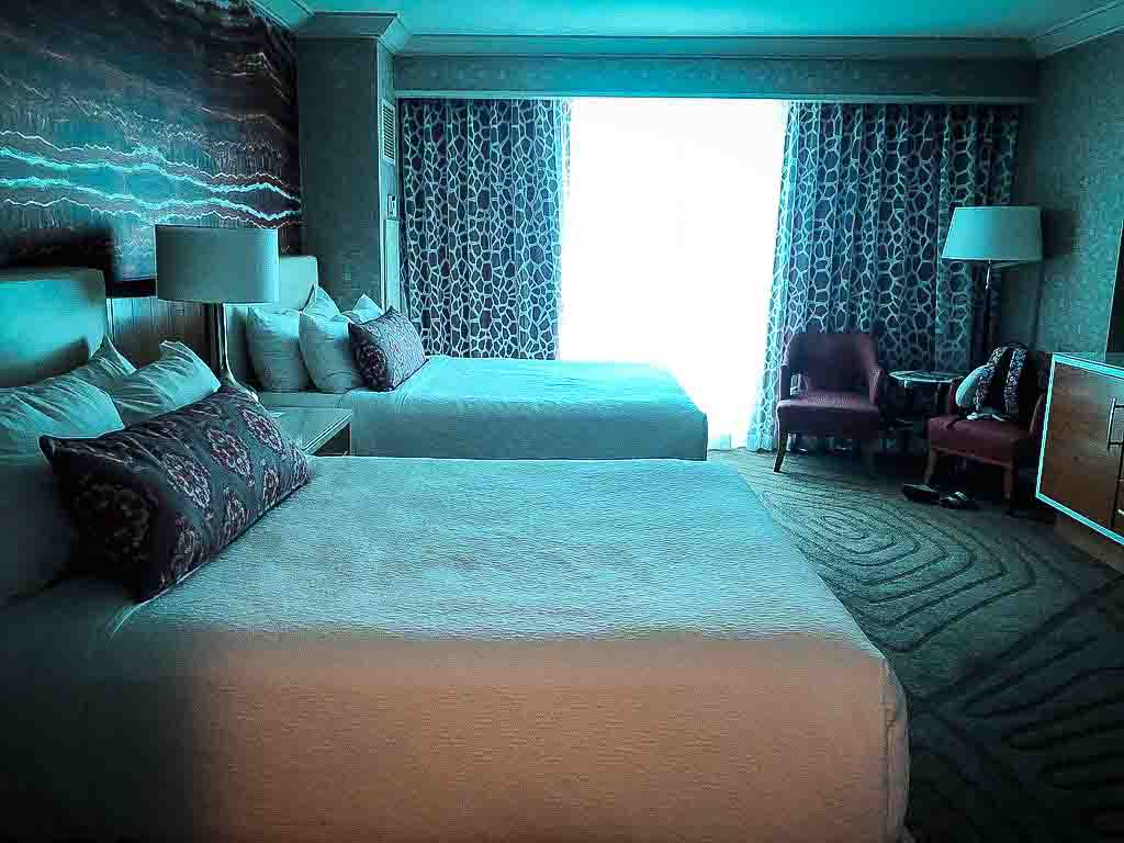 two queen sized beds with white linen and purple cusions at mandalay bay hotel