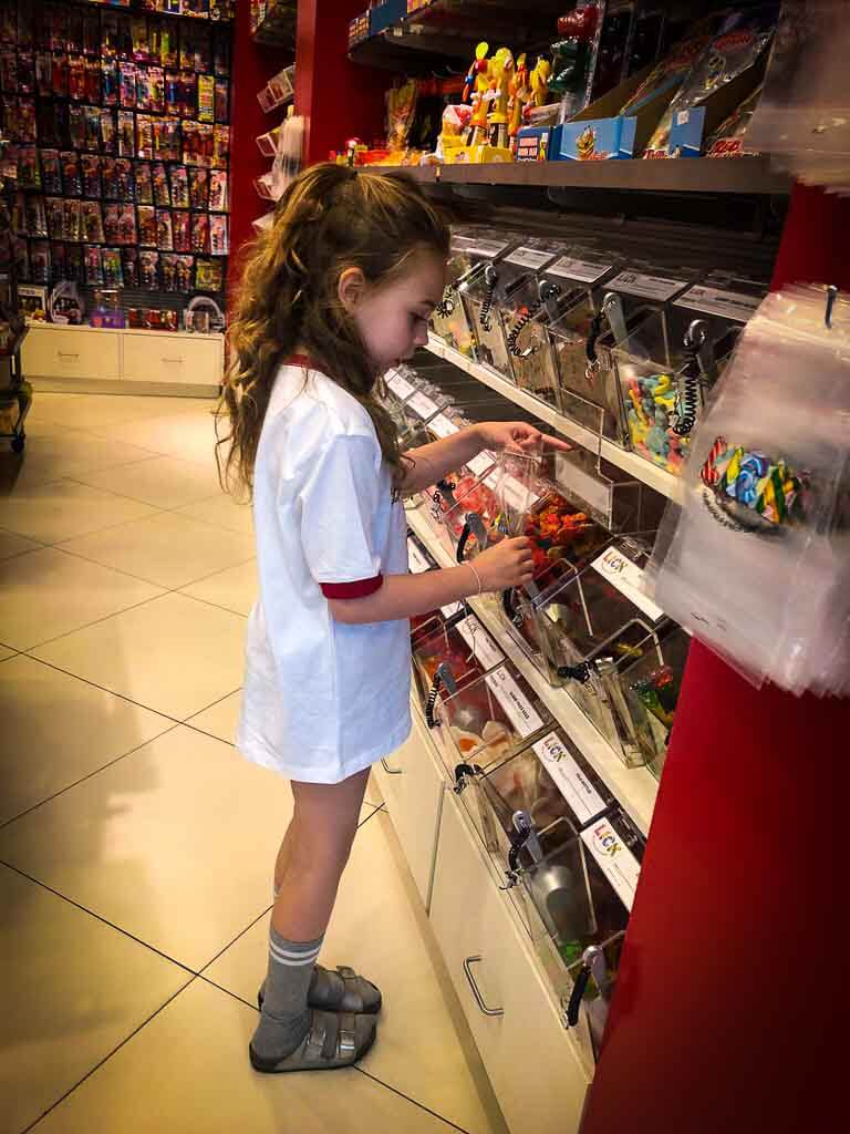 girl with curly hair in big white t shirt choosing sweets at lick sweet shop