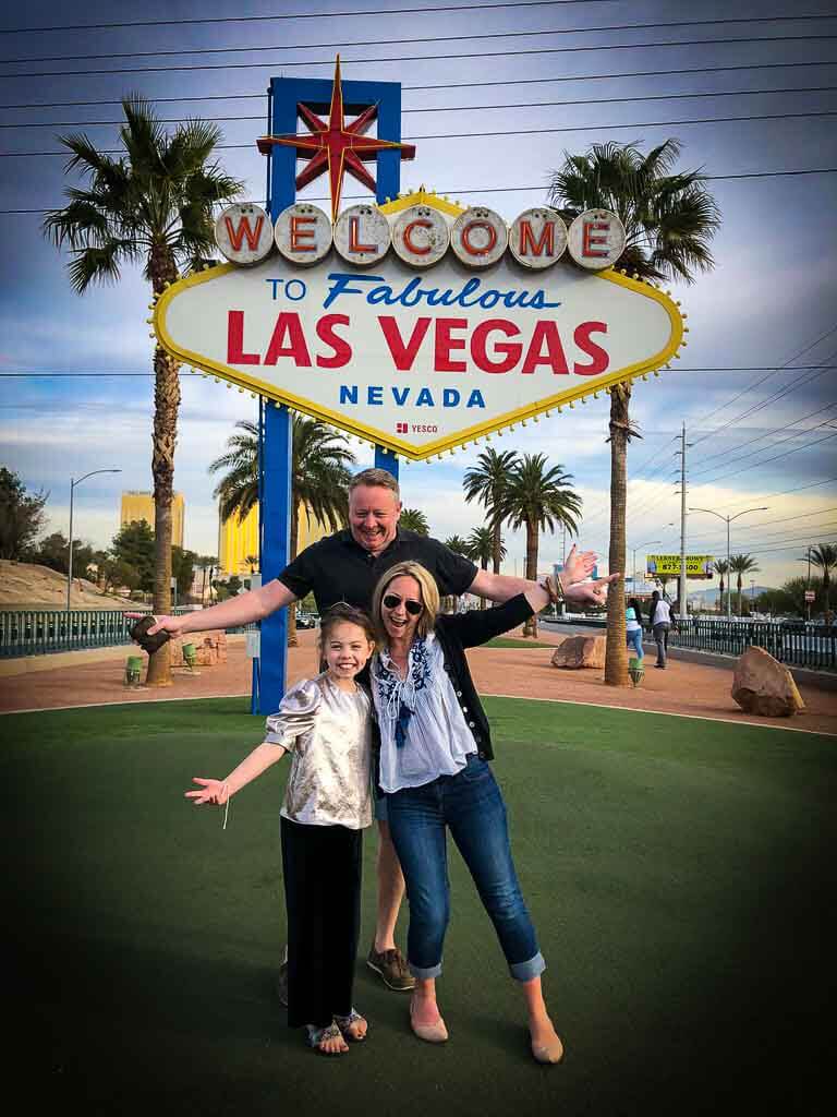 family of 3 posing outside the las vegas sign