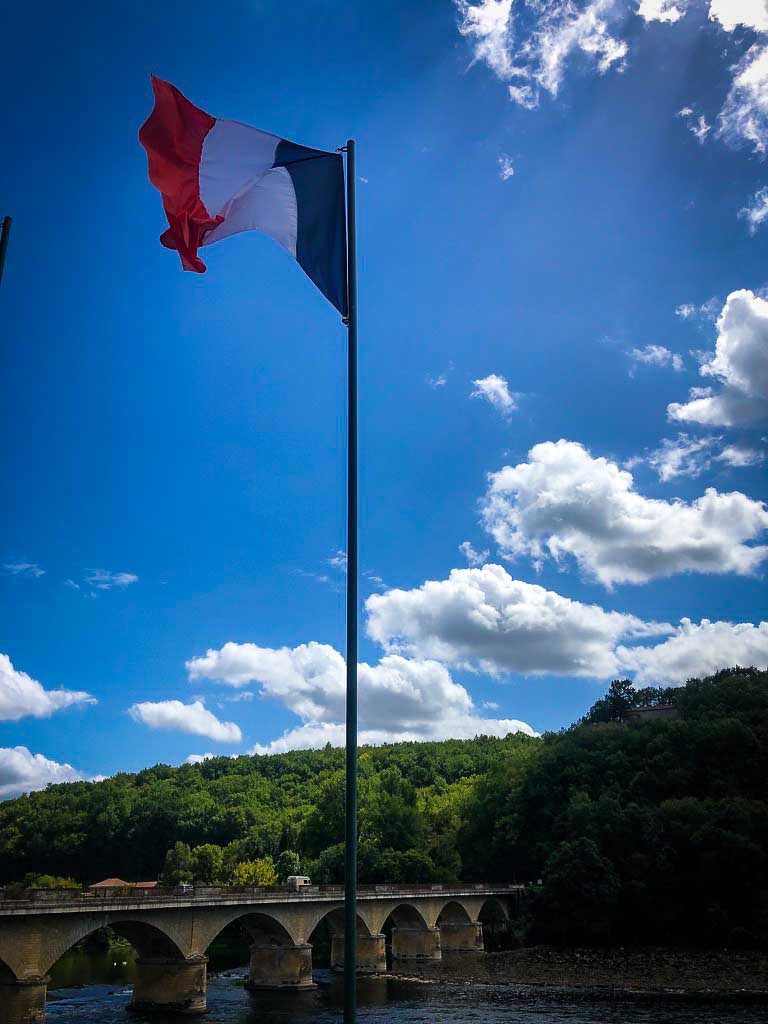 french flag against a blue sky with a few clouds