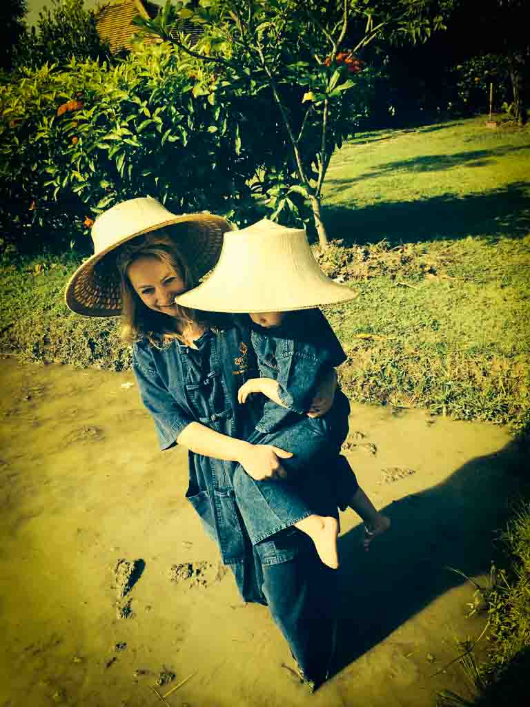 mother in traditional thai farmer clothes holding her daughter is a rice field in Chang Mai