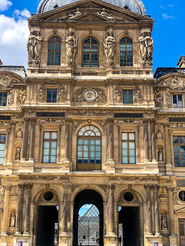 louvre glass pyramid seen through an old building