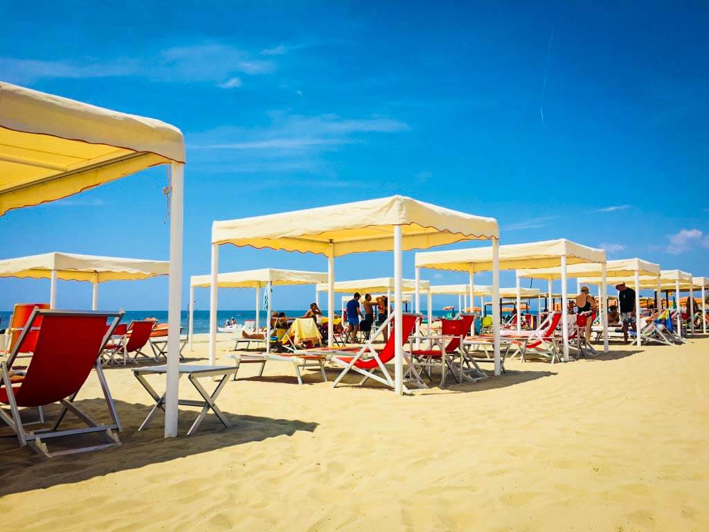 day beds with shaded covers laid out in a line on viareggio beach