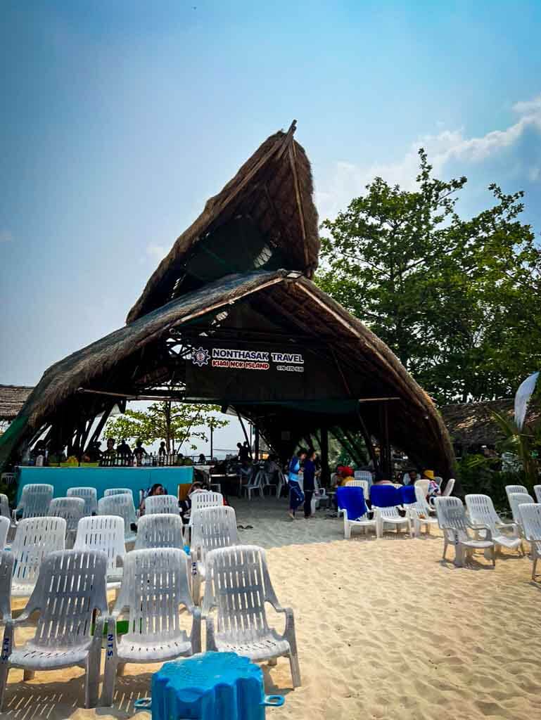 thatched wooden archway infront of plastic chairs on Khai island