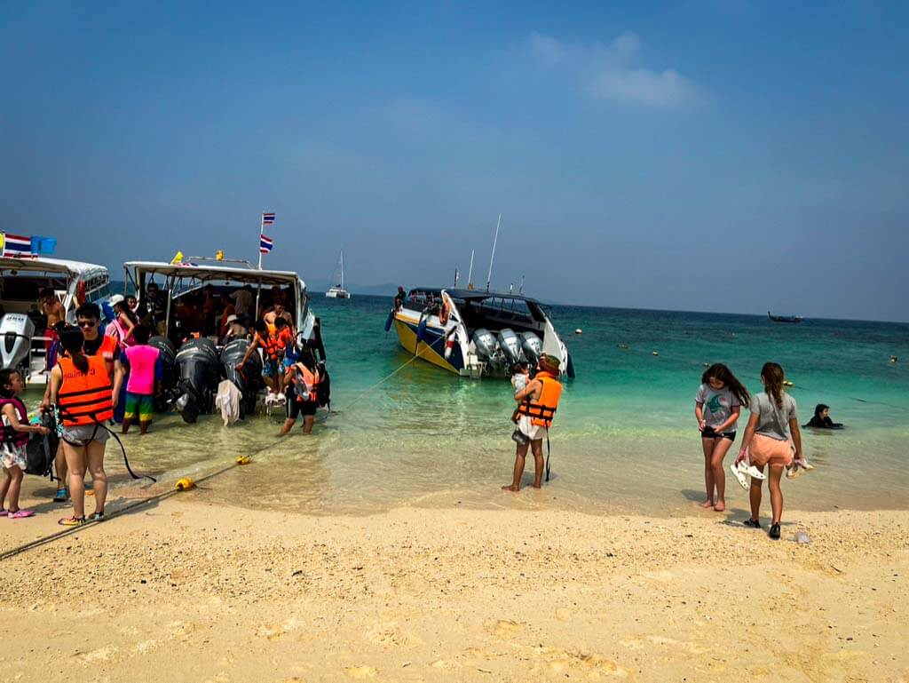 lots of people getting on a speed boat in tropical sea from the beach at Koh Khai Nok