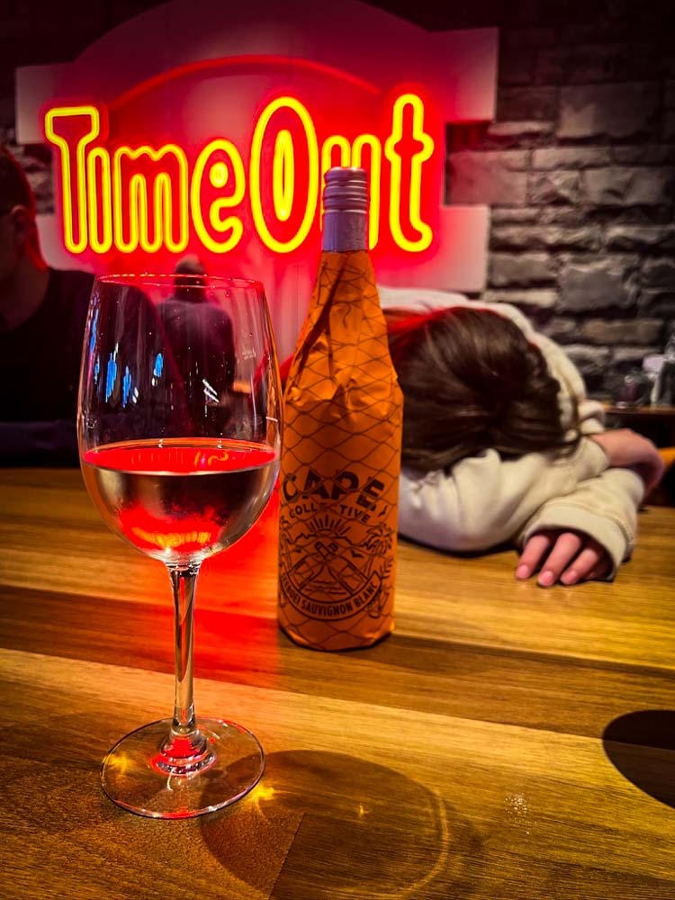 girl sleeping on the table in front of a bottle and glass of wine