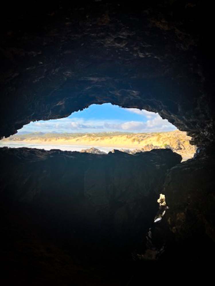 view barely seen of beach through the mouth of a cave