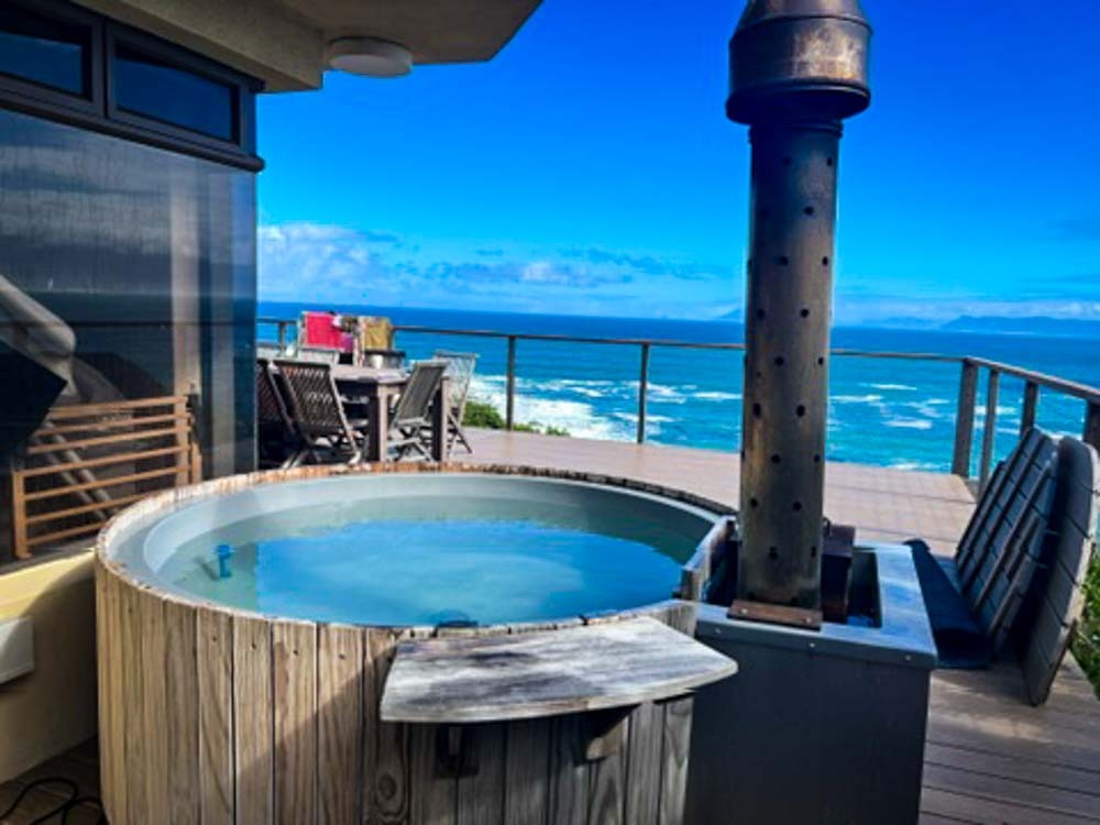 wood fired hot tub over looking a turquoise sea at whale huys
